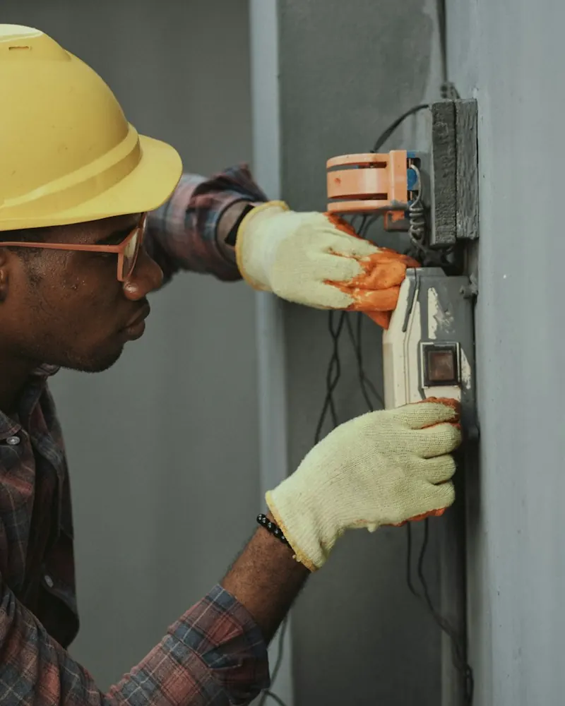 An electrician in a hard hat working on a panel.
